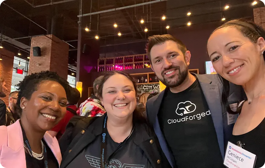 Four people smiling at an evening community event, one in a CloudForged T-shirt